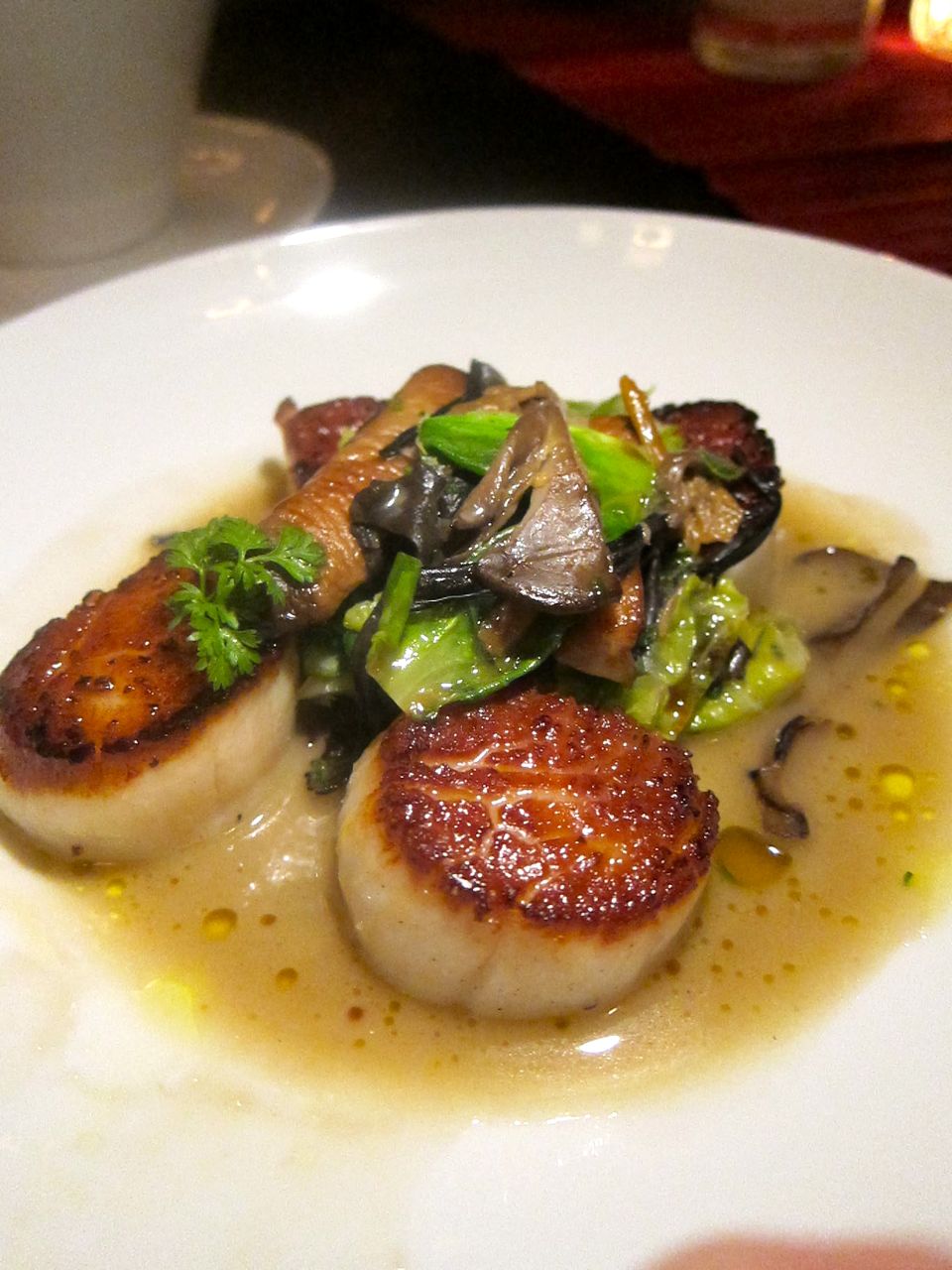 Caramelized scallops surround a toss of wild mushrooms, leeks and Brussels sprouts. Photo: Gael Greene